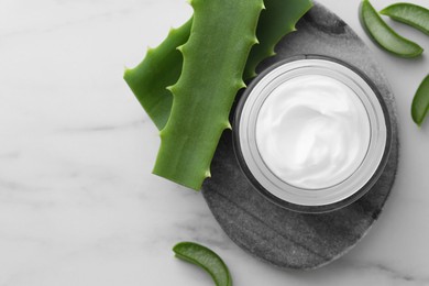 Photo of Jar with cream and cut aloe leaves on white marble table, flat lay. Space for text