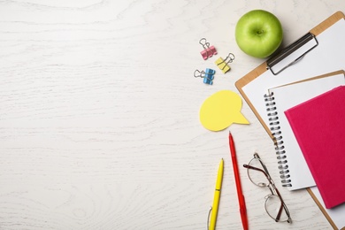 Flat lay composition with apple and stationery on white wooden table, space for text. Teacher's day