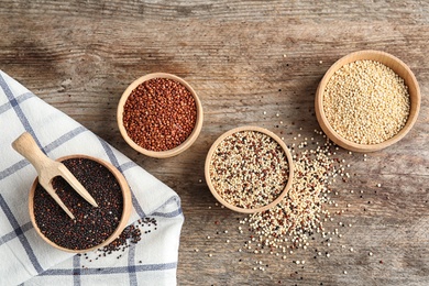 Photo of Bowls with different types of quinoa on wooden background, top view