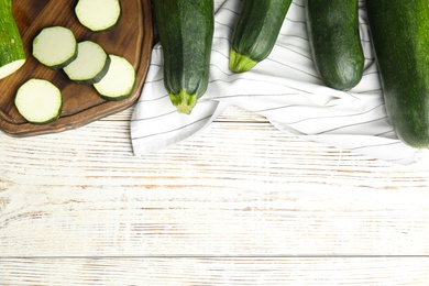 Photo of Flat lay composition with fresh ripe green zucchinis on white wooden table, space for text