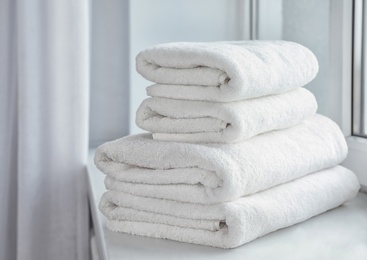 Photo of Stack of fresh soft towels on windowsill