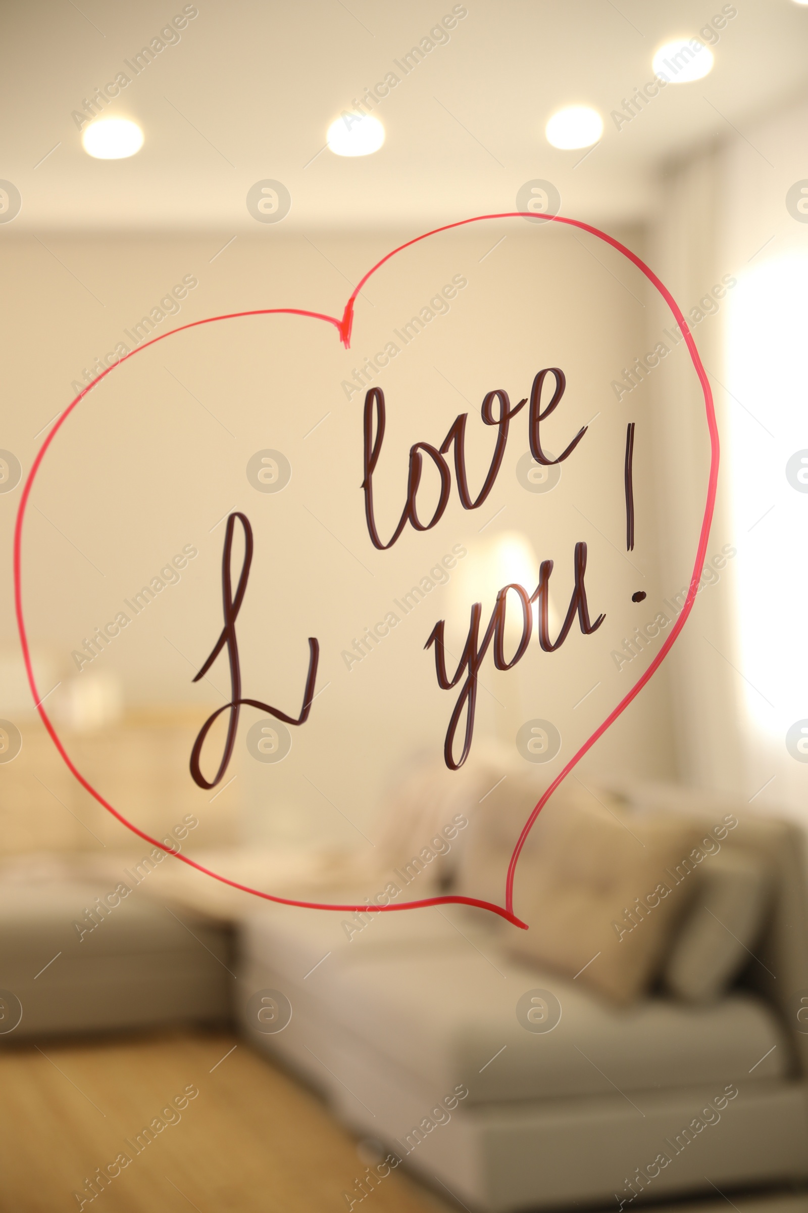Photo of Drawn red heart with handwritten text I Love You on mirror in room. Romantic message