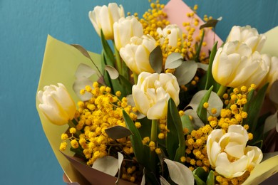 Photo of Bouquet of beautiful spring flowers near turquoise wooden wall, closeup