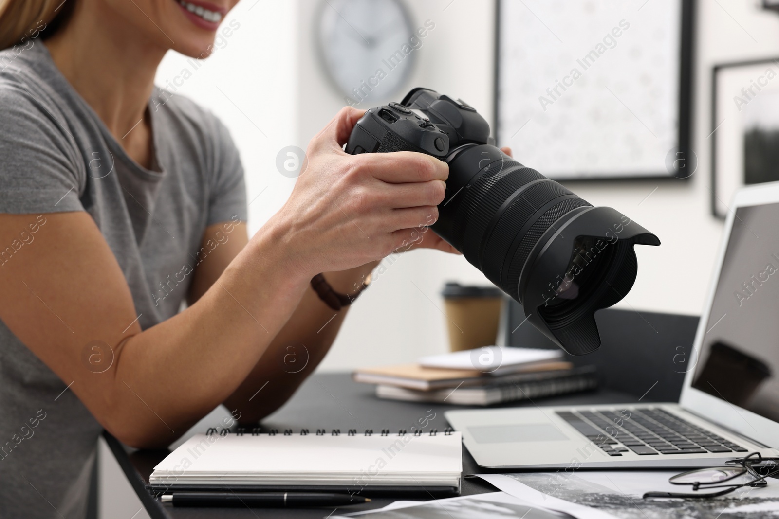 Photo of Professional photographer with digital camera at table in office, closeup