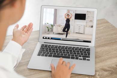 Image of Woman watching morning exercise video on laptop at table, closeup