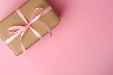 Beautiful gift box with bow on pink background, top view. Space for text