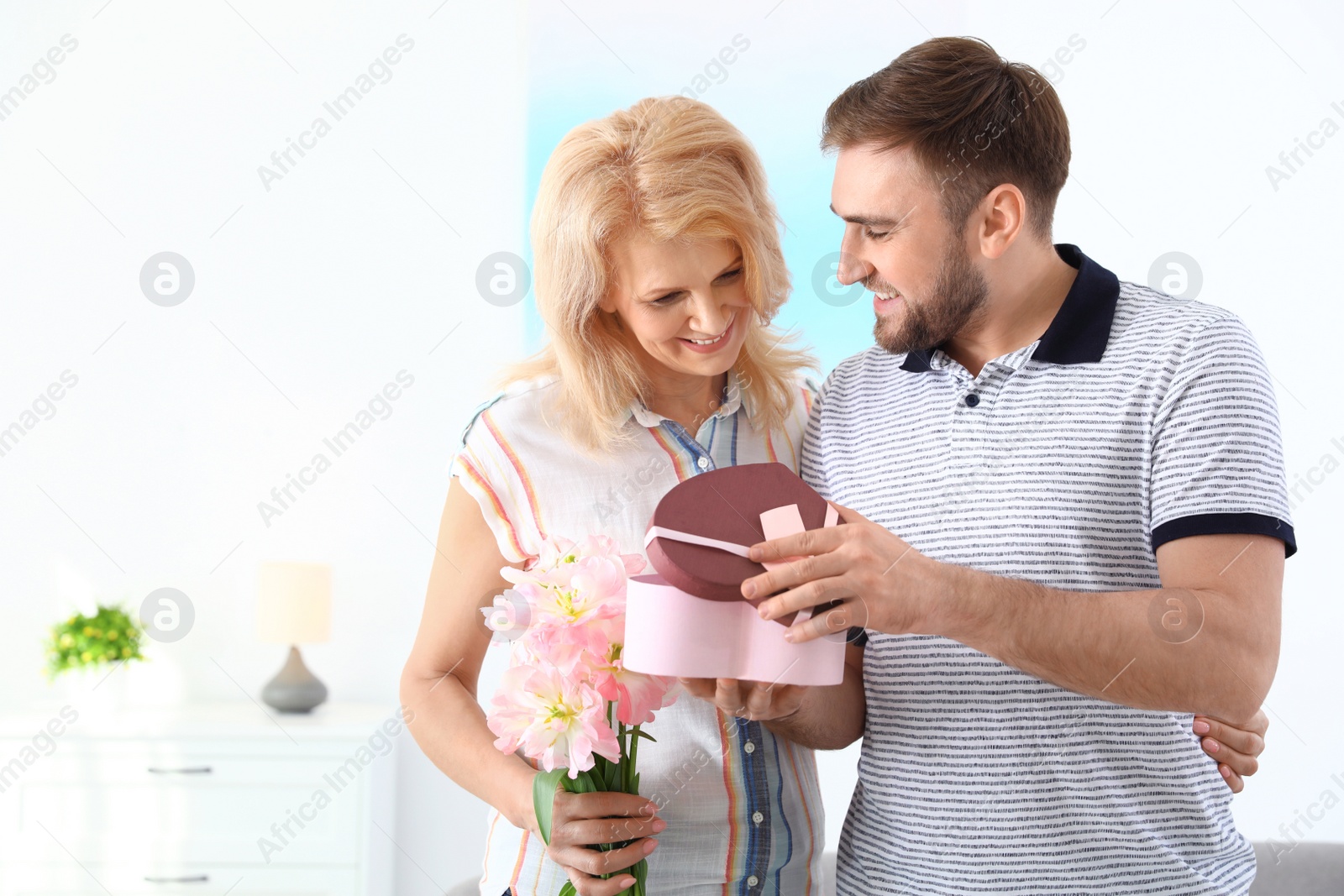 Photo of Young man congratulating his mature mom at home, space for text. Happy Mother's Day