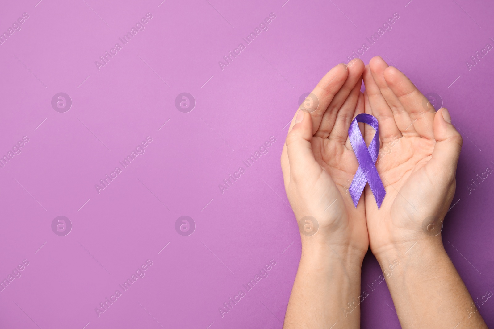 Photo of Woman holding purple ribbon on lilac background, top view with space for text. Domestic violence awareness