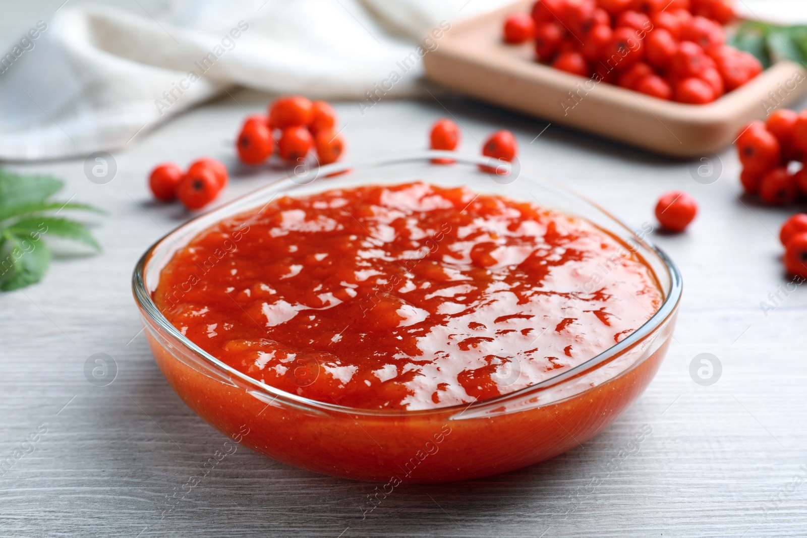 Photo of Delicious rowan jam in bowl  on white wooden table