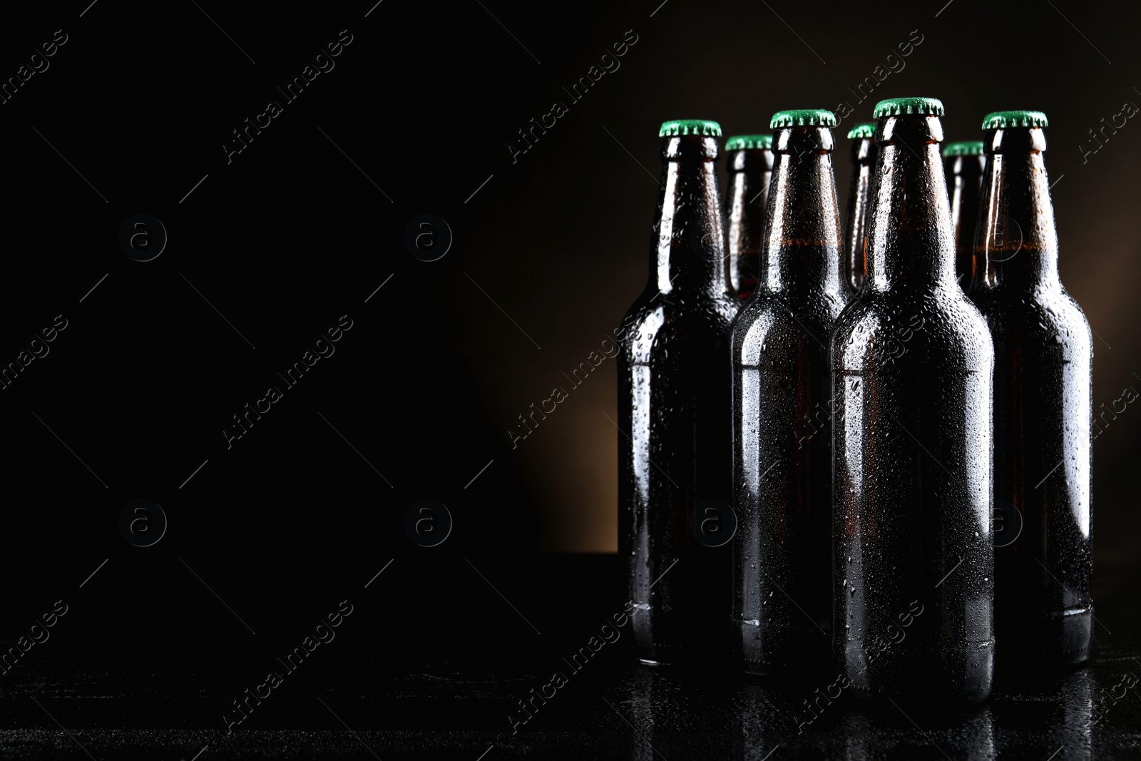 Photo of Many bottles of beer on table against dark background, space for text
