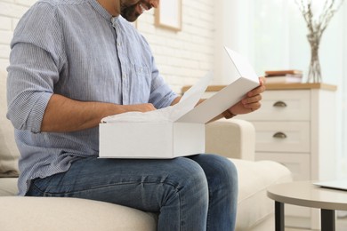 Man unpacking parcel at home, closeup. Online shopping