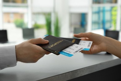 Agent giving passports and tickets to man at check-in desk in airport, closeup