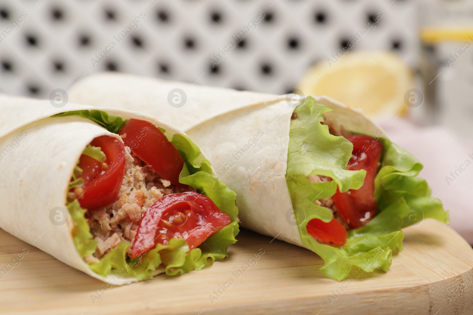 Photo of Delicious tortilla wraps with tuna on wooden board, closeup