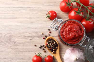 Photo of Jar of tasty tomato paste and ingredients on wooden table, flat lay. Space for text