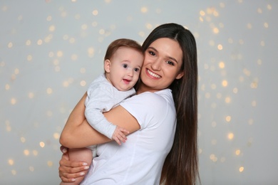 Photo of Portrait of young mother and her adorable baby against defocused lights