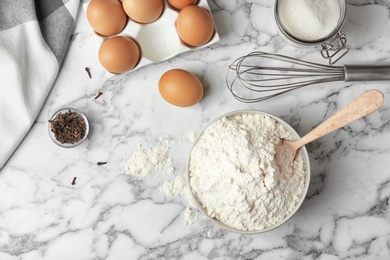 Photo of Bowl with flour, eggs and sugar on light grey background, top view