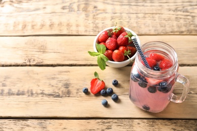 Photo of Natural lemonade with berries in mason jar on wooden table