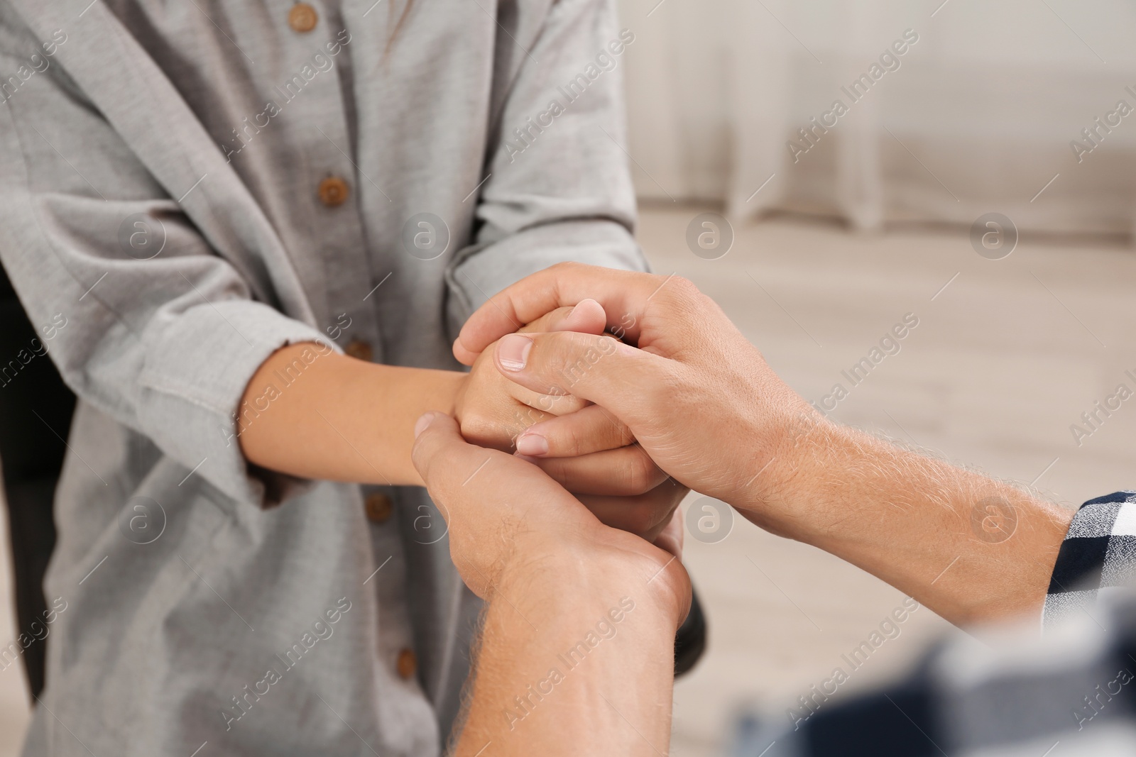 Photo of Man holding woman's hands indoors, closeup. Concept of support and help