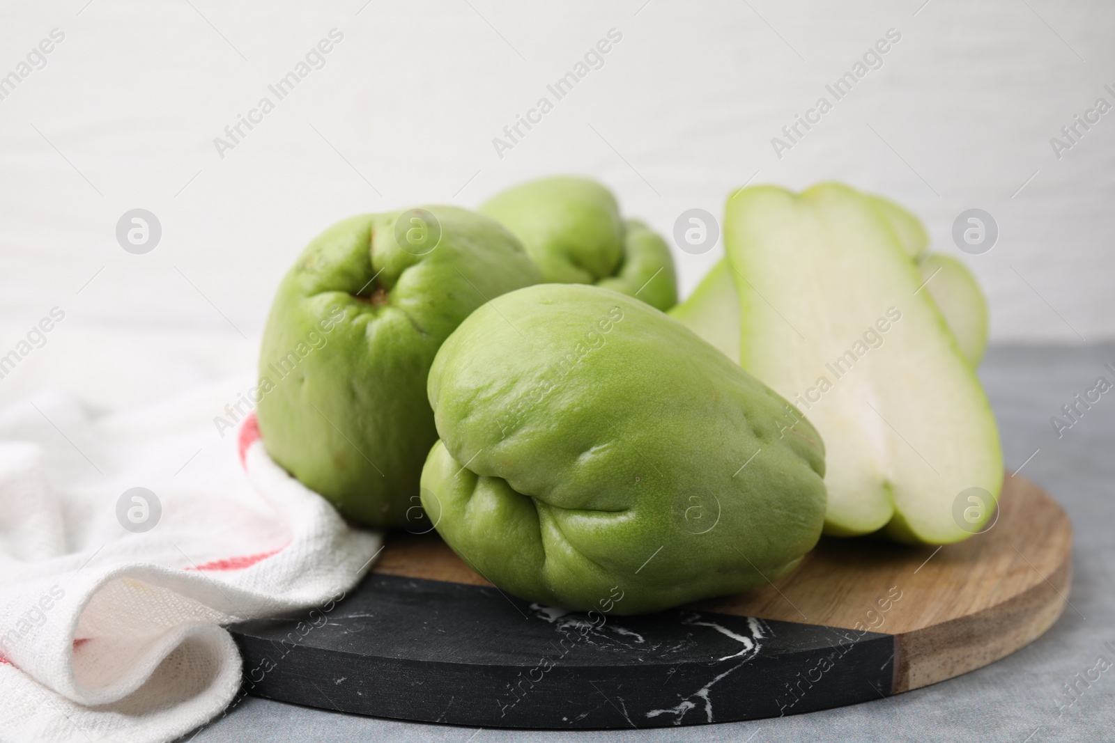 Photo of Cut and whole chayote on gray table, closeup