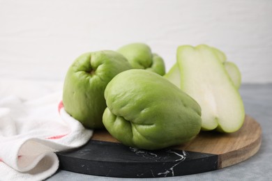 Cut and whole chayote on gray table, closeup