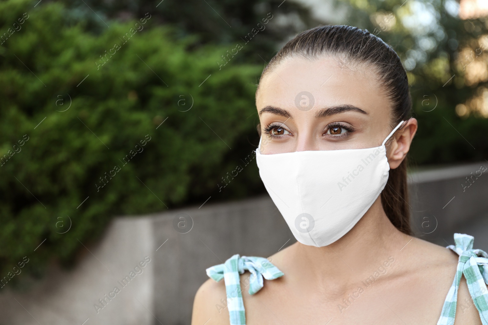 Photo of Woman wearing handmade cloth mask outdoors, space for text. Personal protective equipment during COVID-19 pandemic