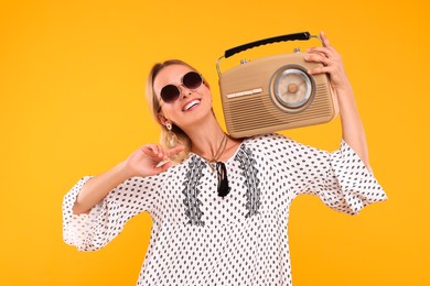 Photo of Portrait of happy hippie woman with retro radio receiver on yellow background