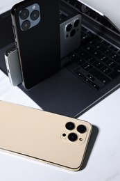 Modern laptop and smartphones on white table, closeup