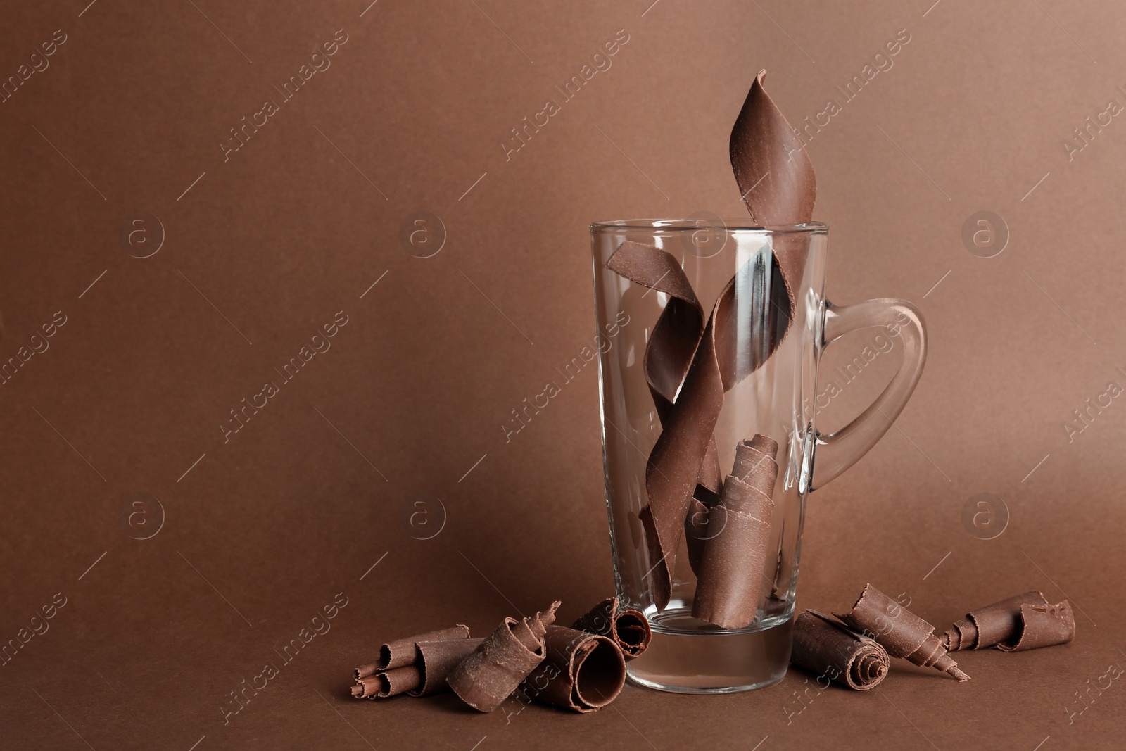 Photo of Glass cup and chocolate curls on color background. Space for text