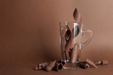 Photo of Glass cup and chocolate curls on color background. Space for text