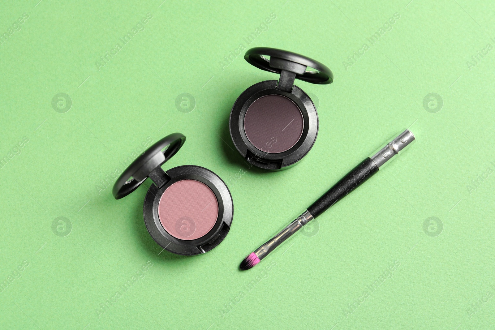 Photo of Eye shadows and brush on color background, flat lay