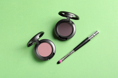 Photo of Eye shadows and brush on color background, flat lay