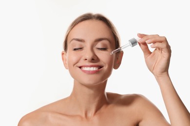 Photo of Beautiful woman applying cosmetic serum onto her face on white background