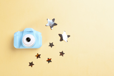 Toy camera and stars on beige background, flat lay