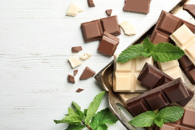 Flat lay composition with different kinds of chocolate on light table. Space for text