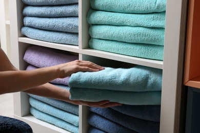 Photo of Woman putting towels on shelf, closeup view