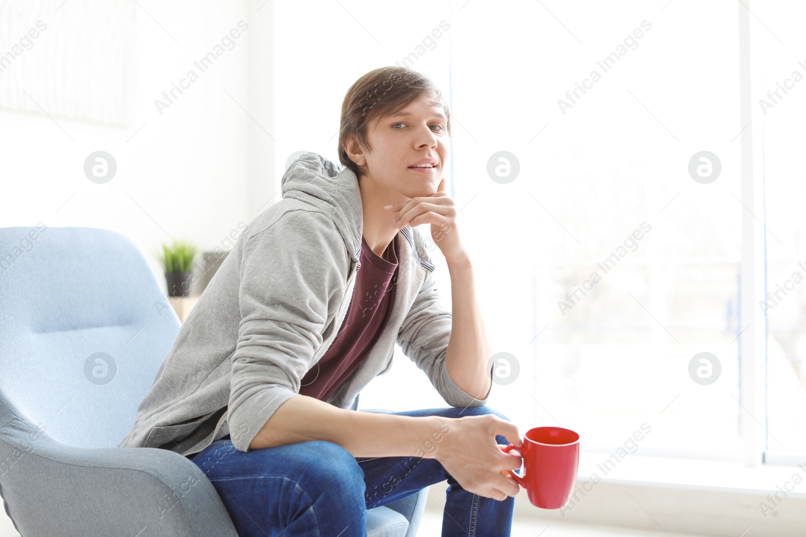 Photo of Portrait of young man drinking coffee in armchair