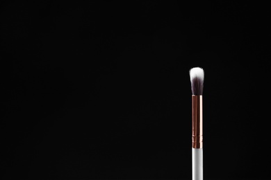 Eyeshadow makeup brush against dark background. Space for text