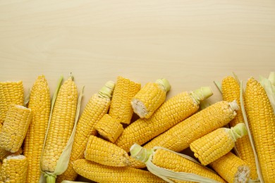 Photo of Tasty fresh corn cobs on wooden table, flat lay. Space for text