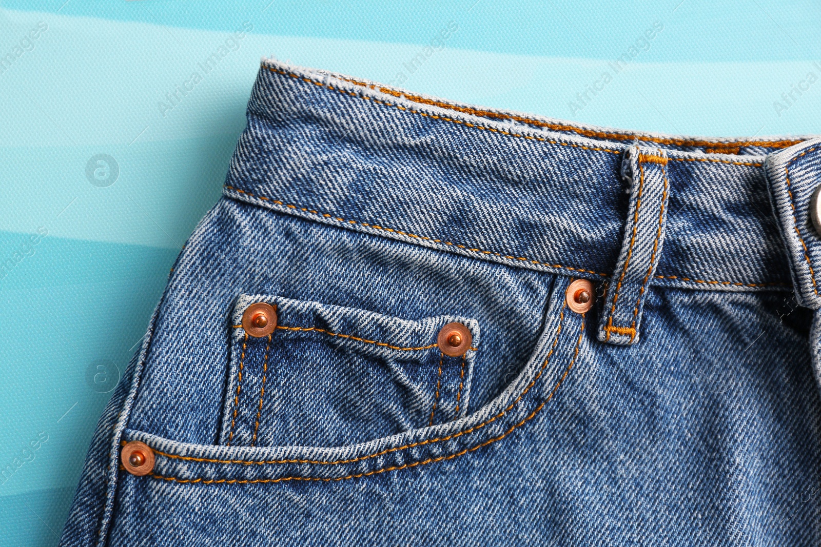 Photo of Stylish blue jeans on color background, closeup of inset pocket