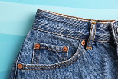 Photo of Stylish blue jeans on color background, closeup of inset pocket