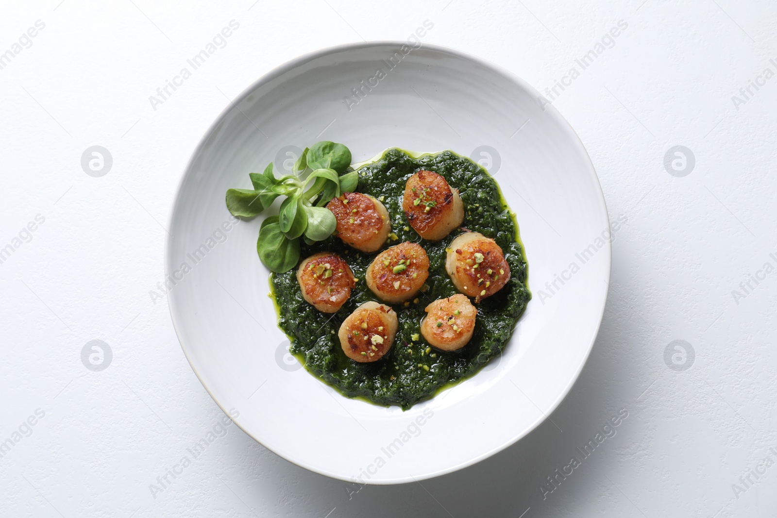 Photo of Delicious fried scallops with tasty sauce and corn salad in bowl isolated on white, top view