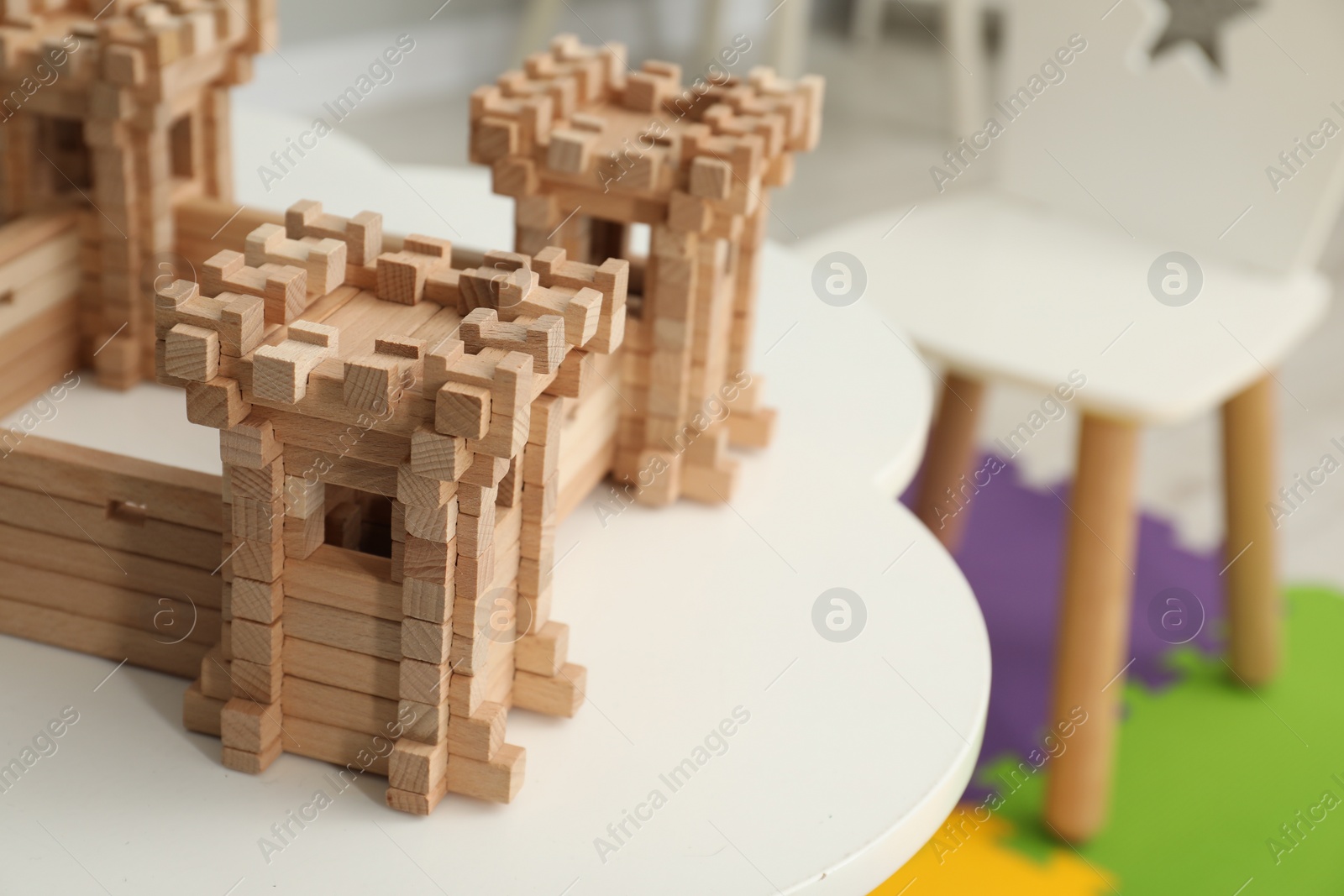 Photo of Wooden fortress on white table indoors, space for text. Children's toy
