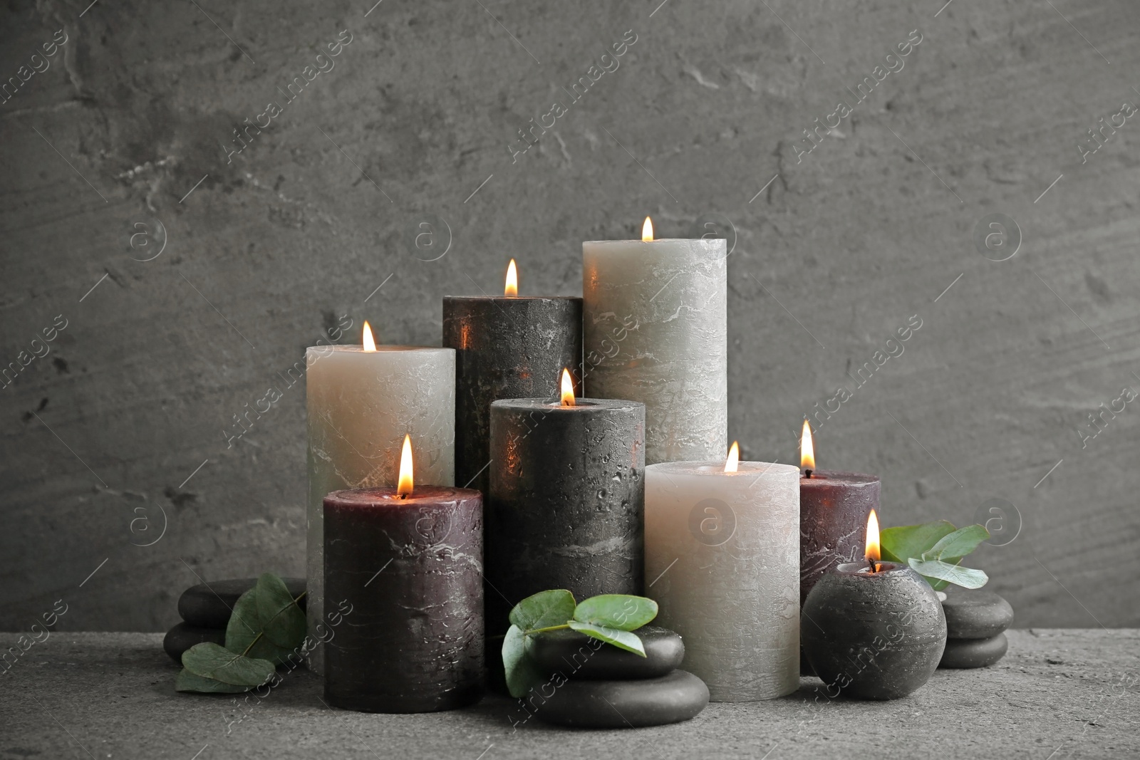 Photo of Composition with burning candles on table against grey background