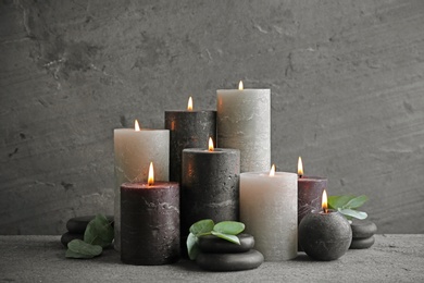 Composition with burning candles on table against grey background