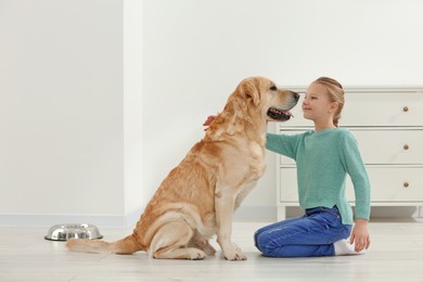 Photo of Cute child with her Labrador Retriever on floor at home. Adorable pet