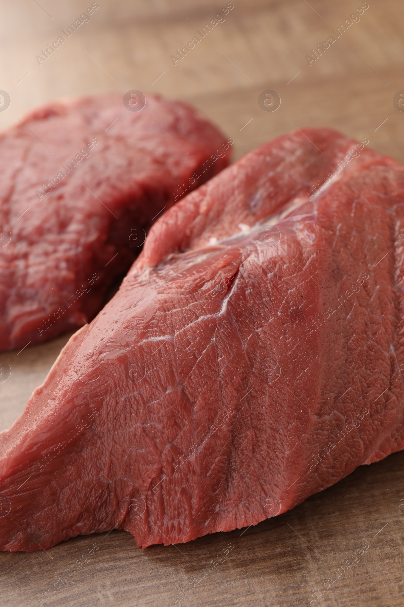 Photo of Pieces of raw beef meat on wooden table, closeup