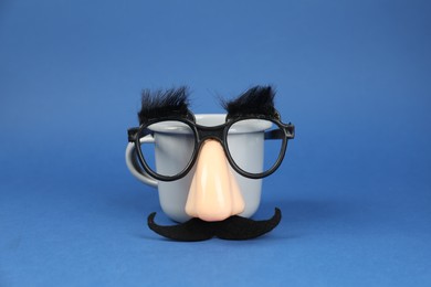 Photo of Man's face made of cup, fake mustache, nose and glasses on blue background