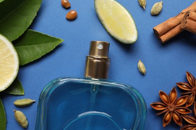 Photo of Flat lay composition with bottle of perfume and fresh citrus fruits on blue background