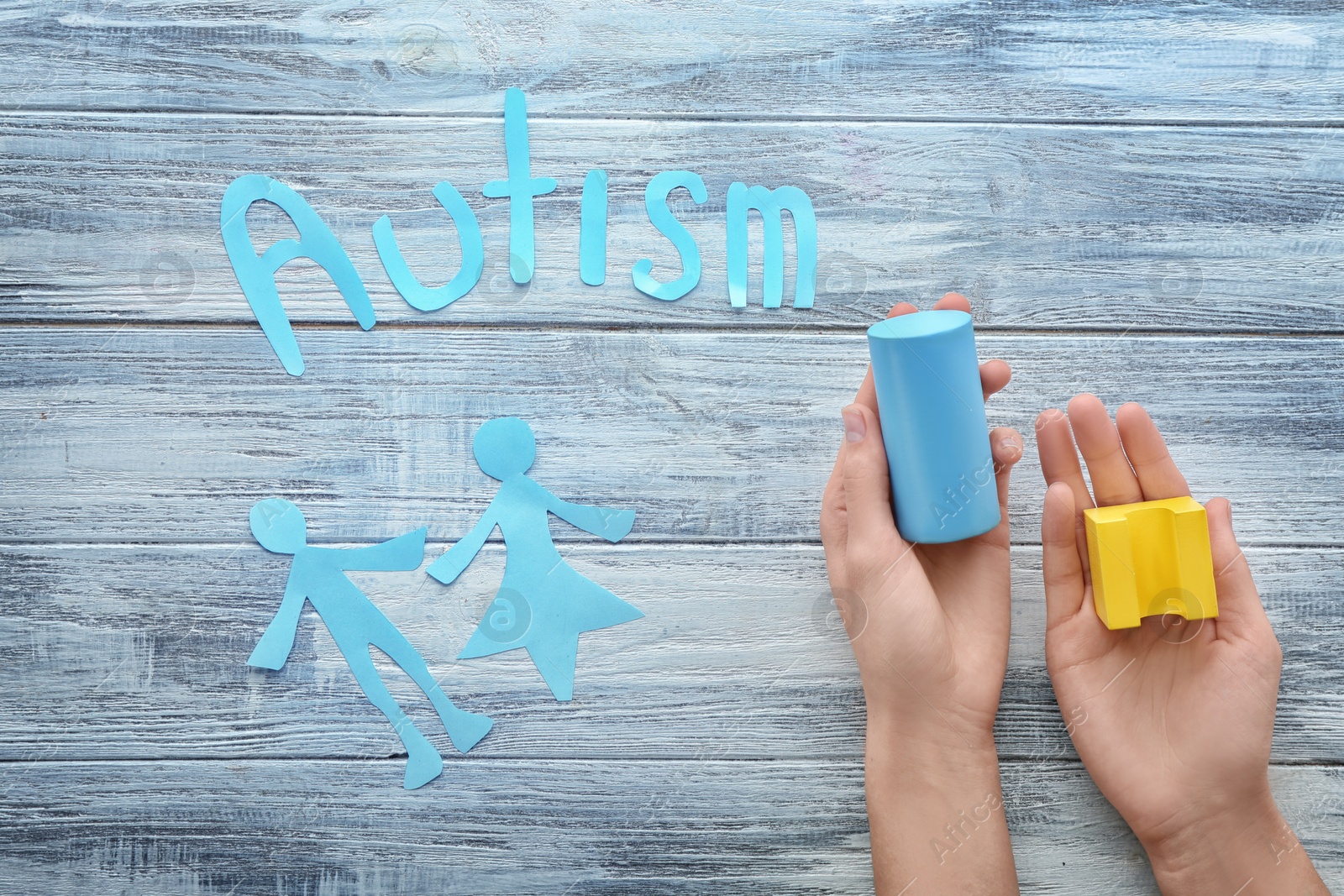 Photo of Woman with building blocks and word "Autism" on wooden background