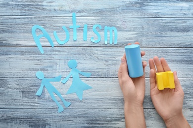 Woman with building blocks and word "Autism" on wooden background